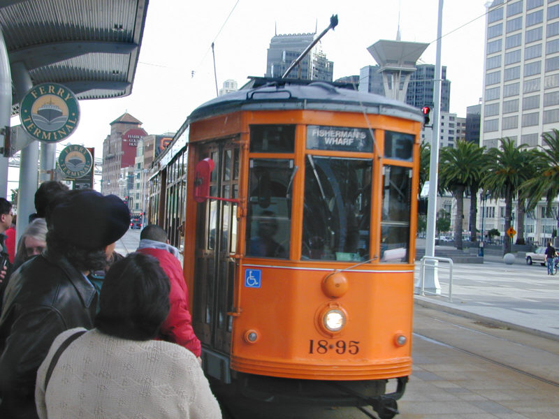 A packed-to-the-gills street car rumbles by on its way to Fishermans Wharf.